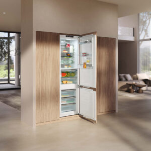 Moderner Miele Einbaukühlschrank mit offener Tür und übersichtlich angeordneten Lebensmitteln, integriert in eine hochwertige Küchenfront aus Holz in hellem Wohnambiente